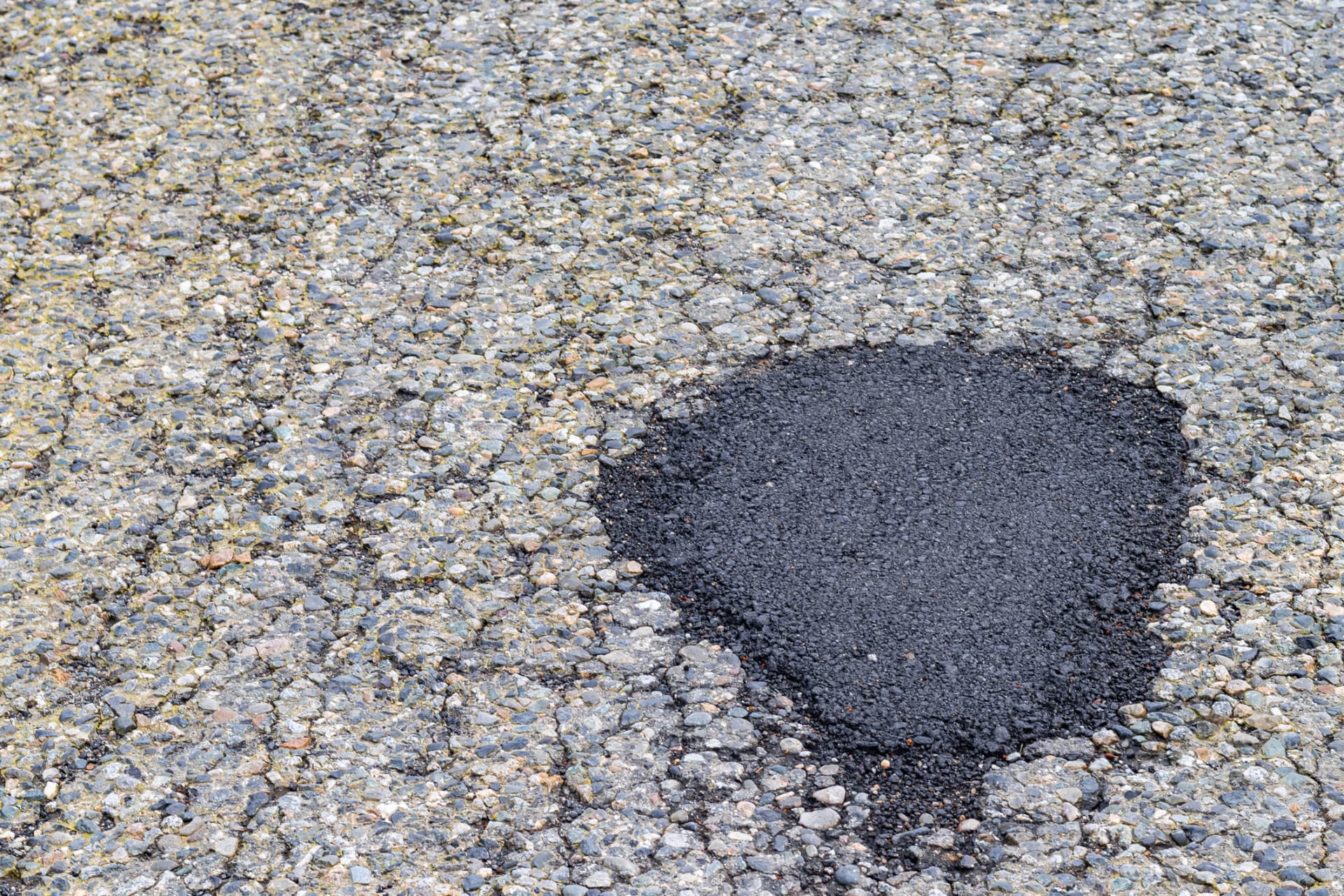 Completed hot-mix pothole repair in a worn asphalt surface in Middletown, NJ