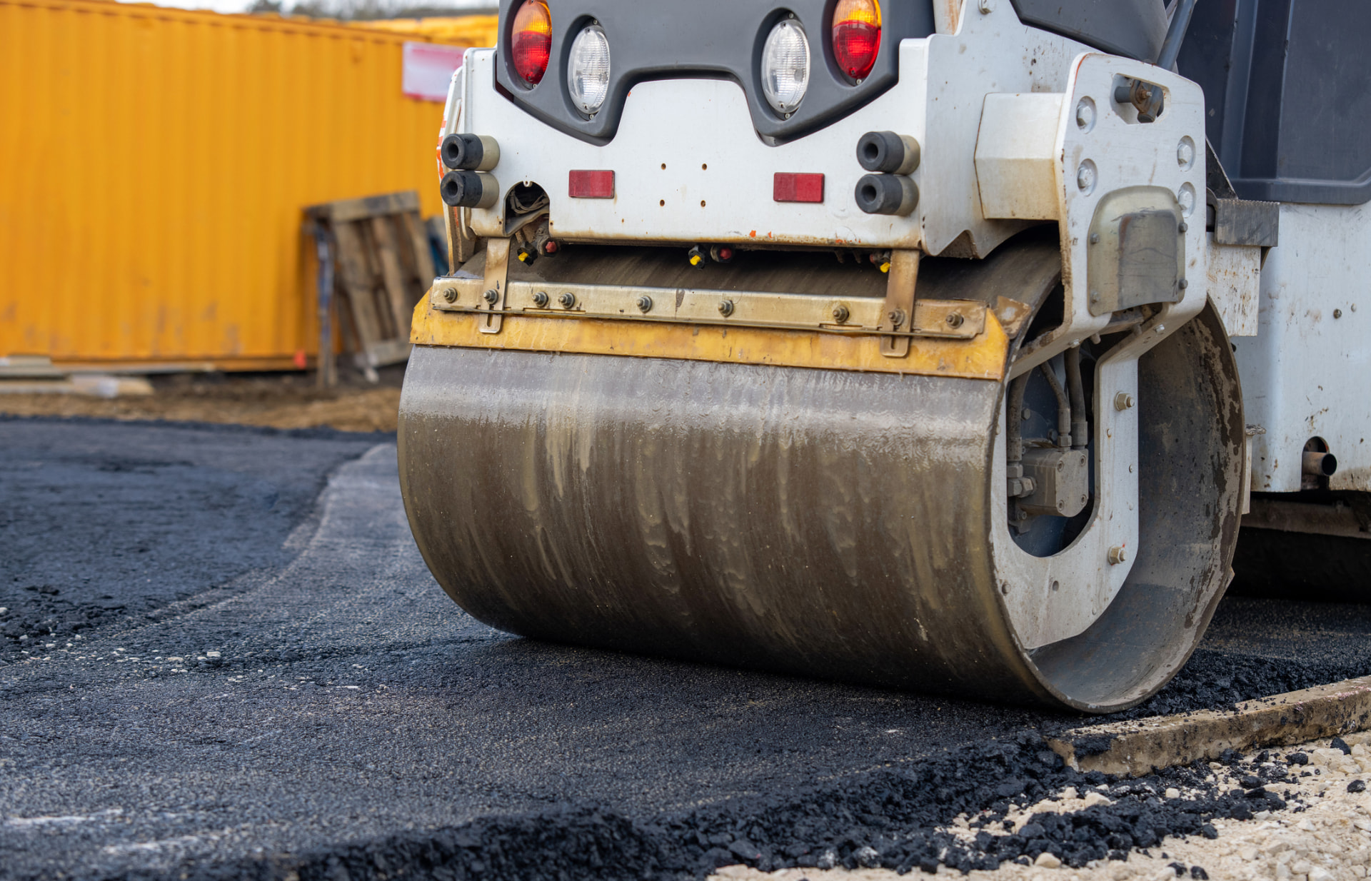Close-up of a roller drum compacting fresh asphalt on a job site