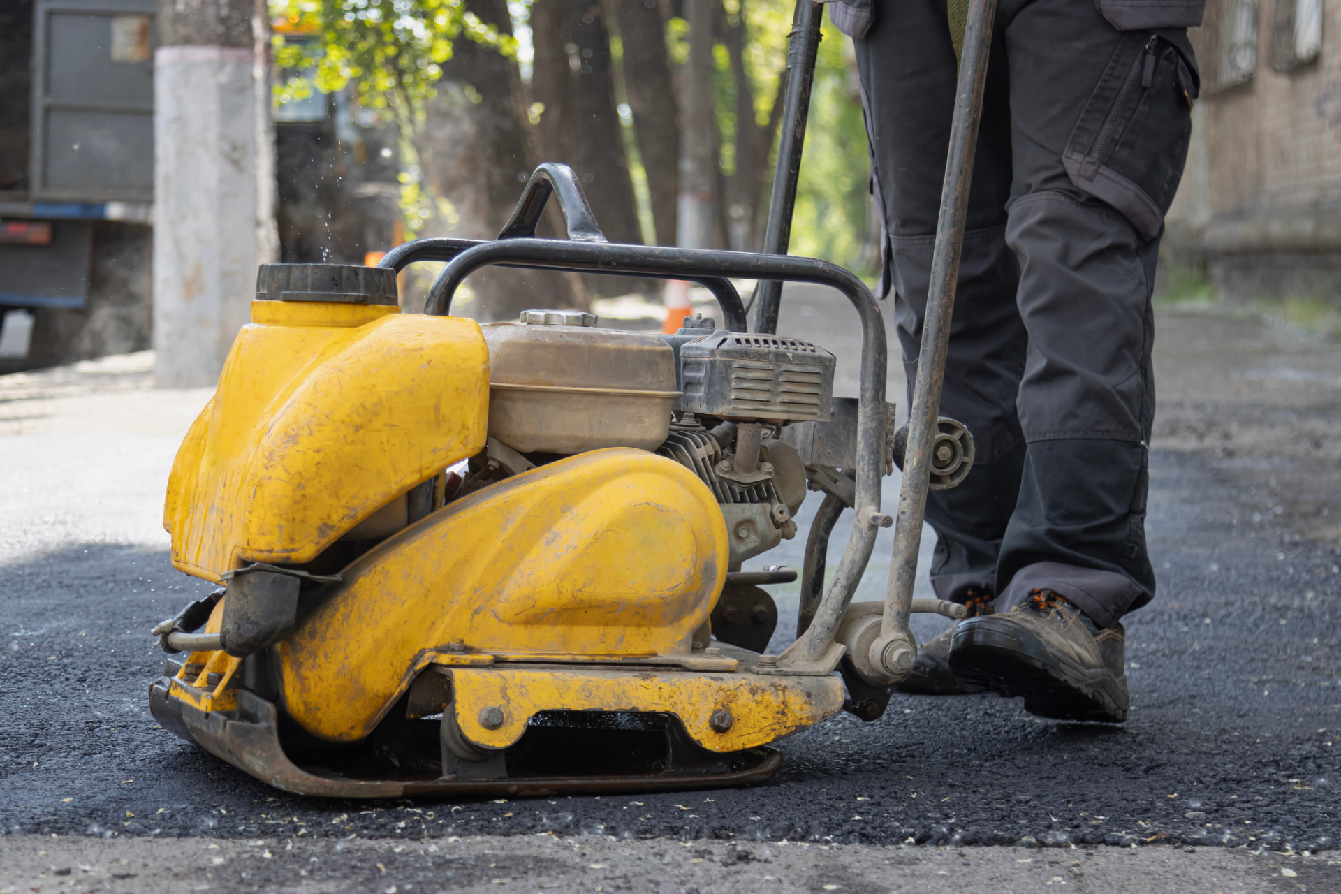 Yellow plate compactor tamping new asphalt on a driveway in Shamong, NJ