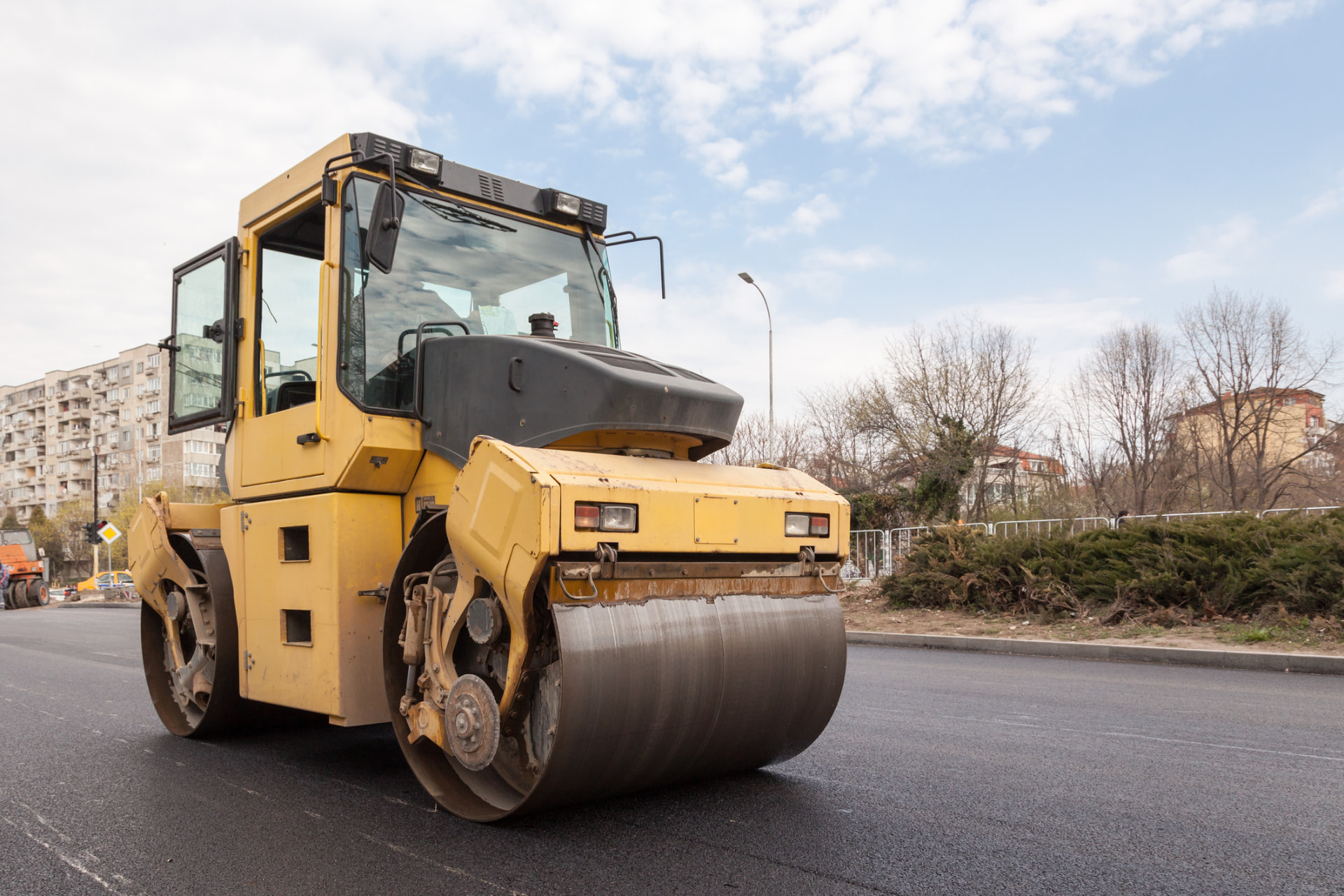 Heavy asphalt roller parked on a newly finished roadway surface