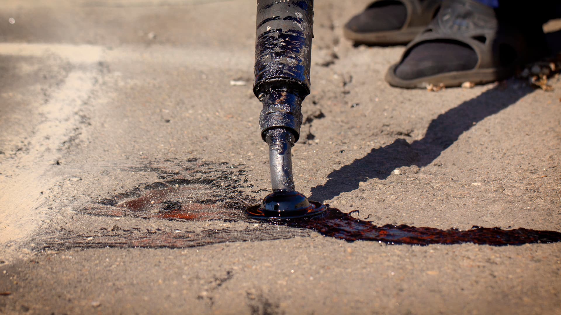 Crack sealing wand applying hot sealant to a cracked asphalt surface