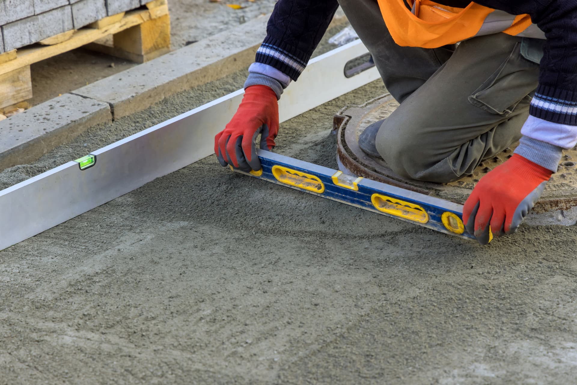 Contractor checking grade and level during asphalt base preparation in Freehold, NJ