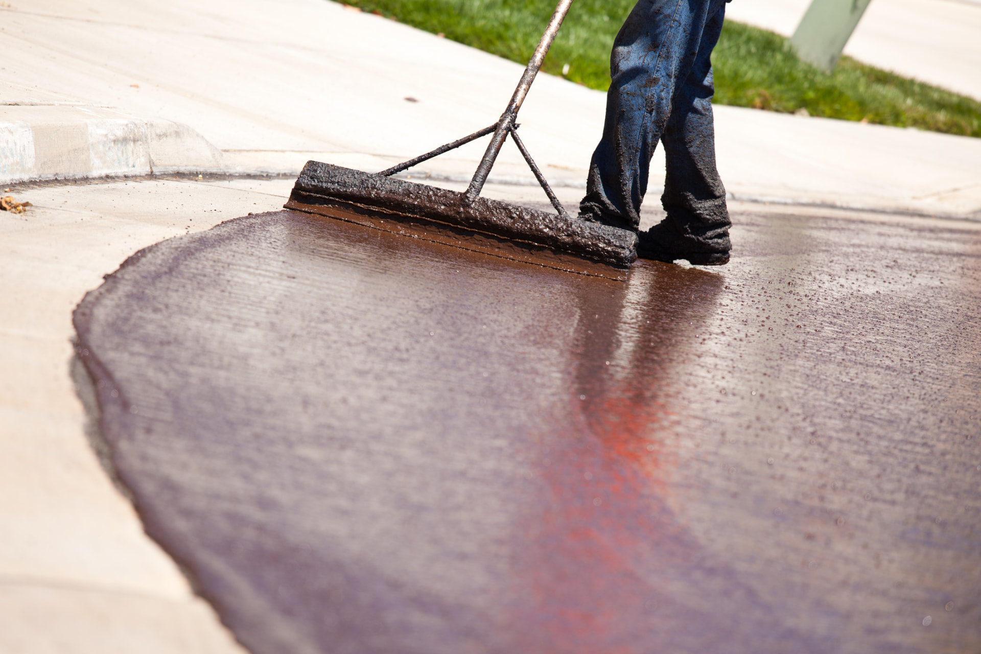 Squeegee spreading fresh sealer across a residential driveway in Toms River