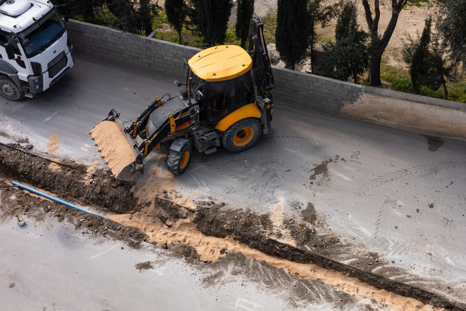 Backhoe backfilling a utility trench before asphalt restoration in Shamong, NJ