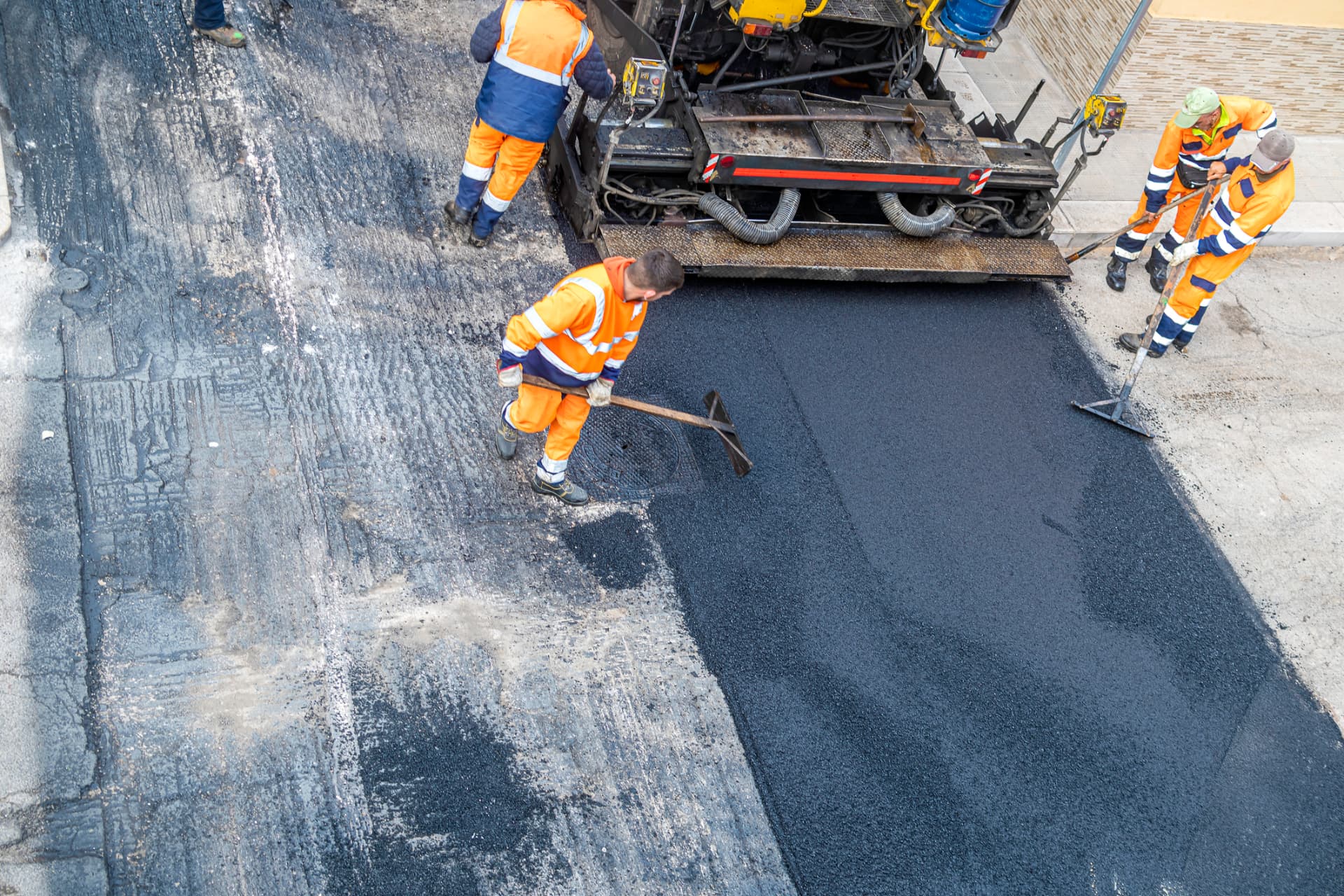 Paving crew raking hot asphalt behind a paver on a New Jersey street