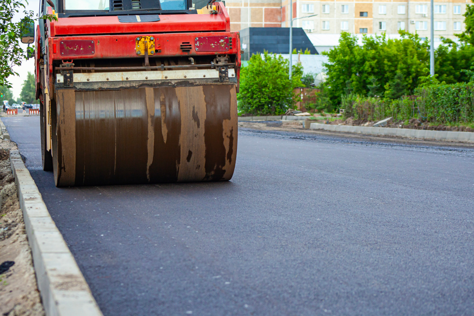 Road roller finishing a smooth new asphalt surface on a private roadway
