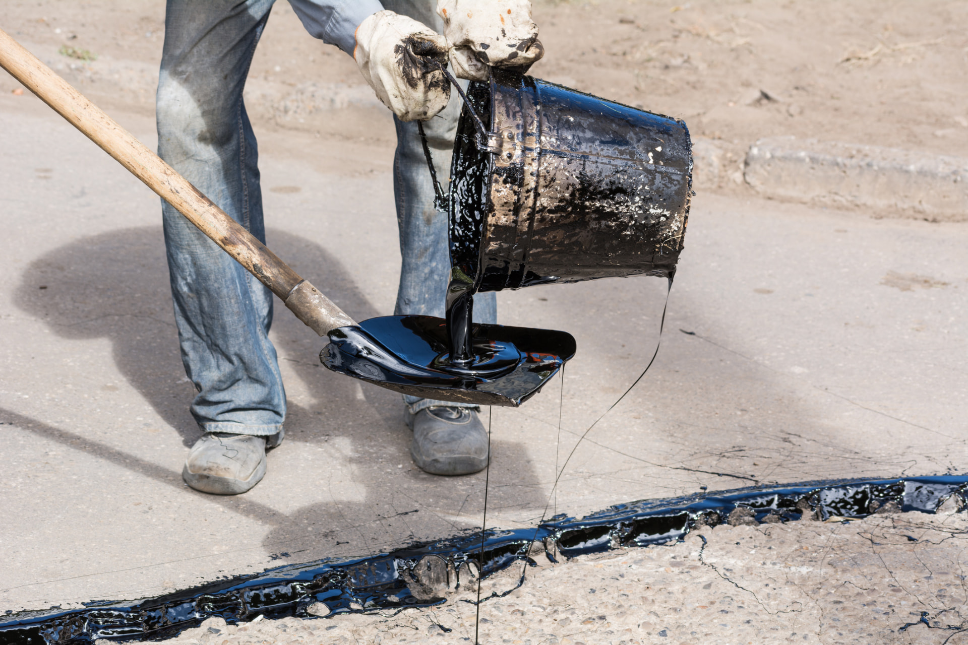 Hot rubberized crack filler being poured into a pavement crack