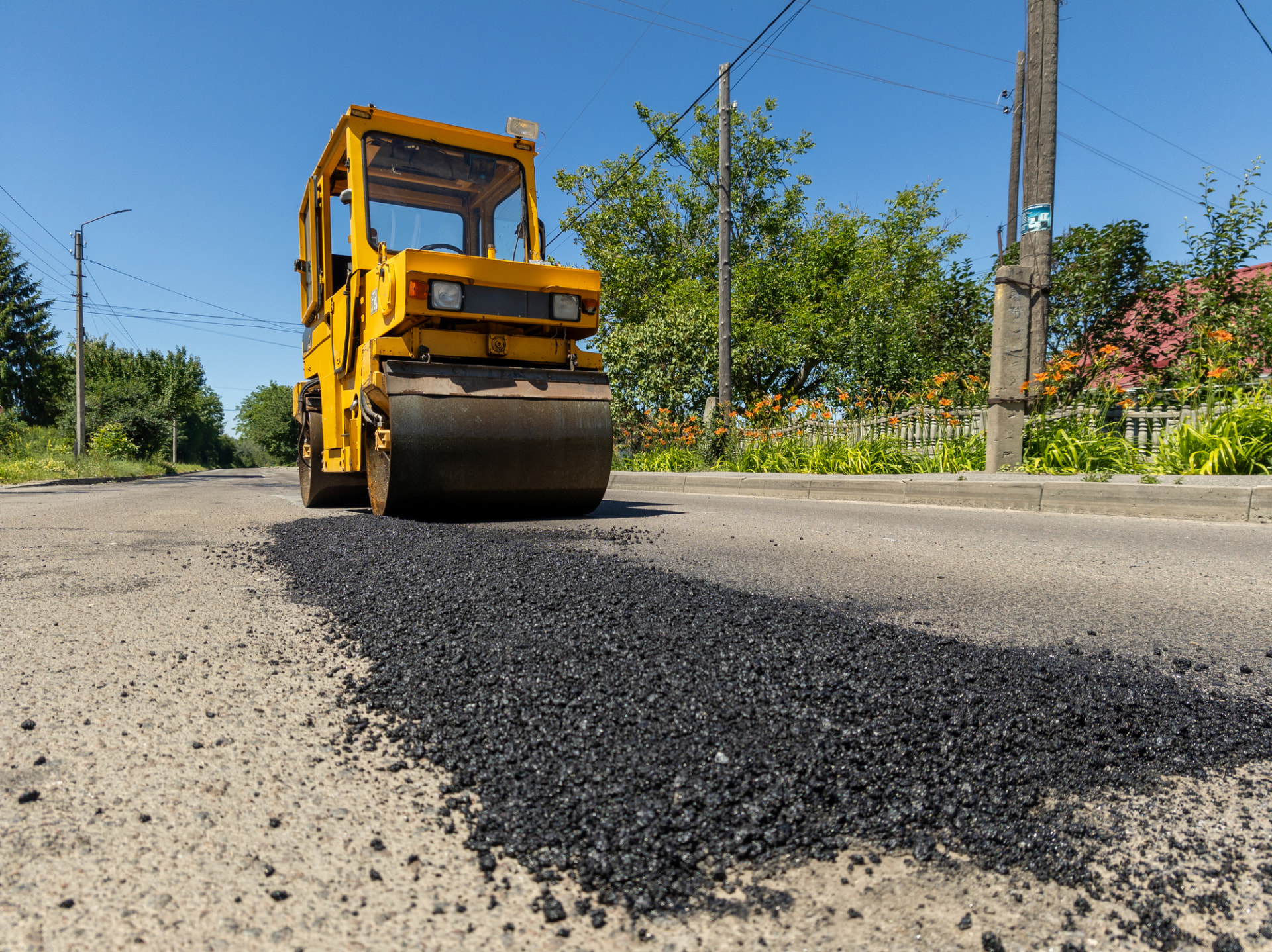 Roller compacting a fresh hot-mix asphalt repair patch on a residential street