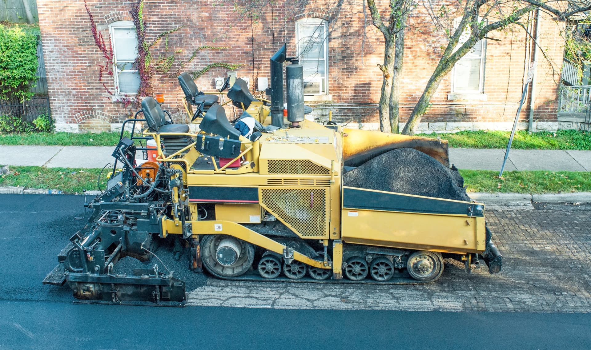 Asphalt paver loaded with hot mix laying a new street surface