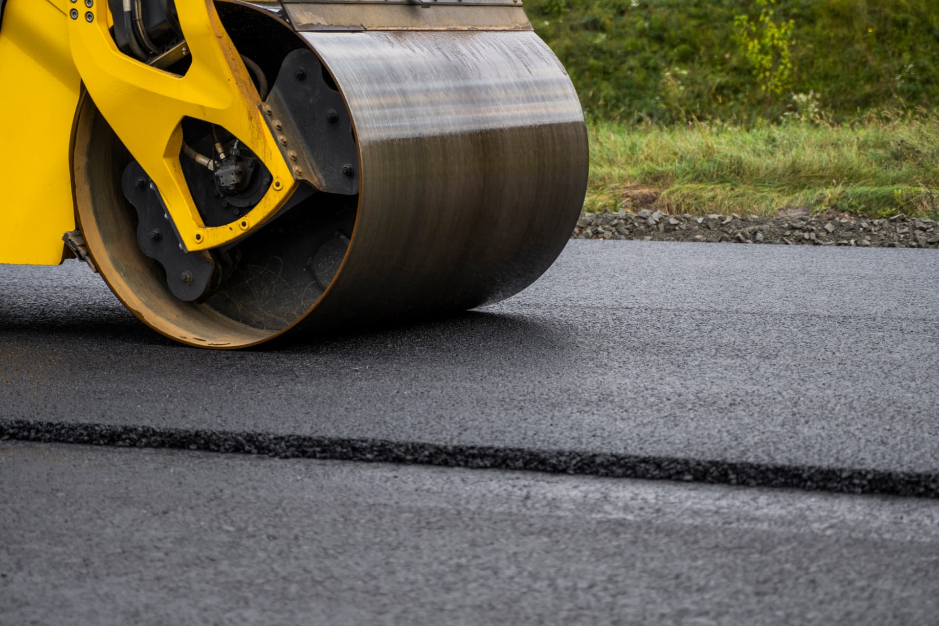 Roller finishing a smooth, sealed black asphalt surface