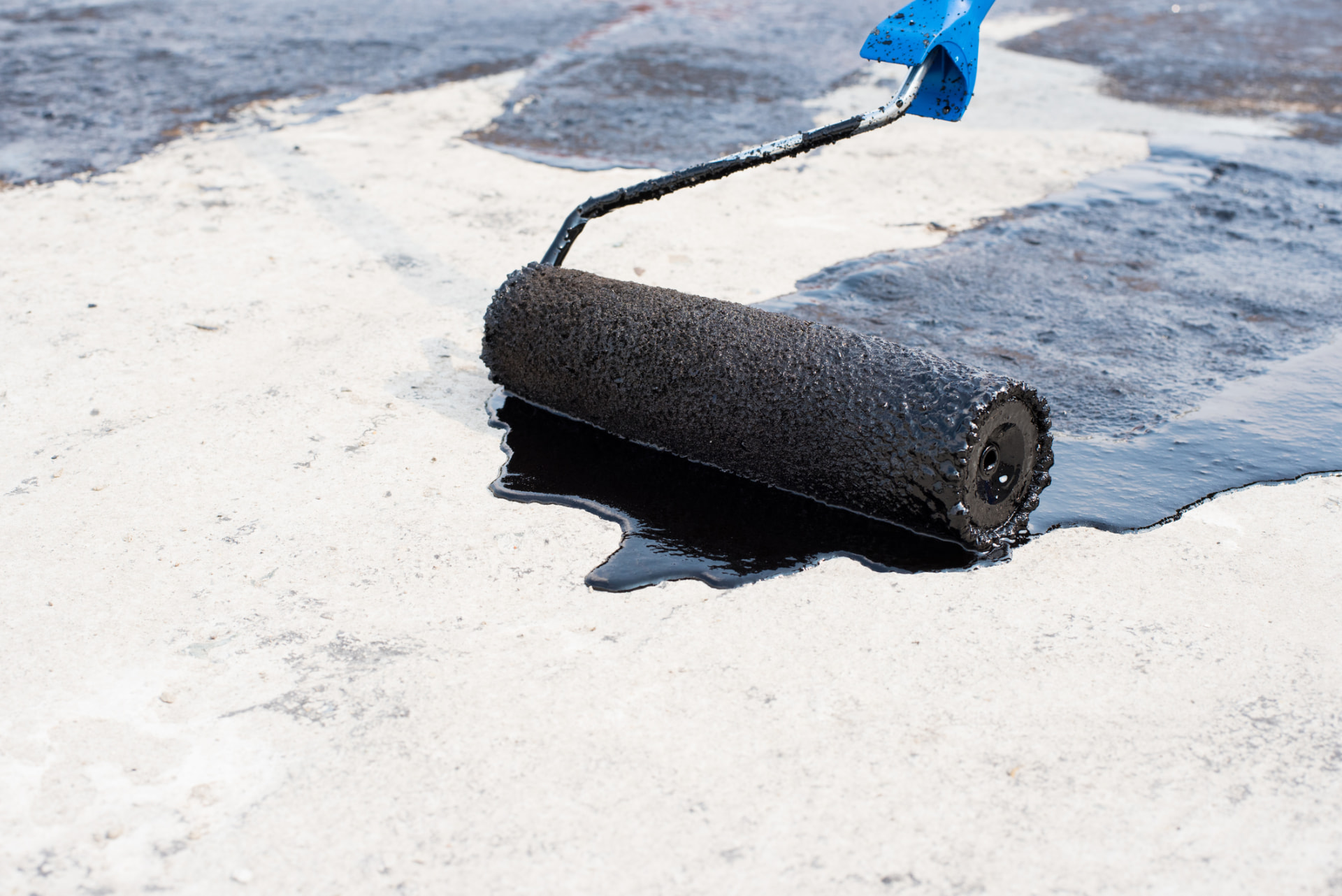 Sealcoat roller spreading fresh sealer across a worn parking surface in Middletown