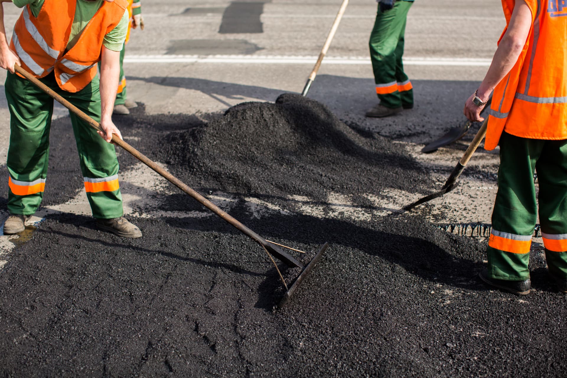 Paving crew raking and spreading hot asphalt on a roadway