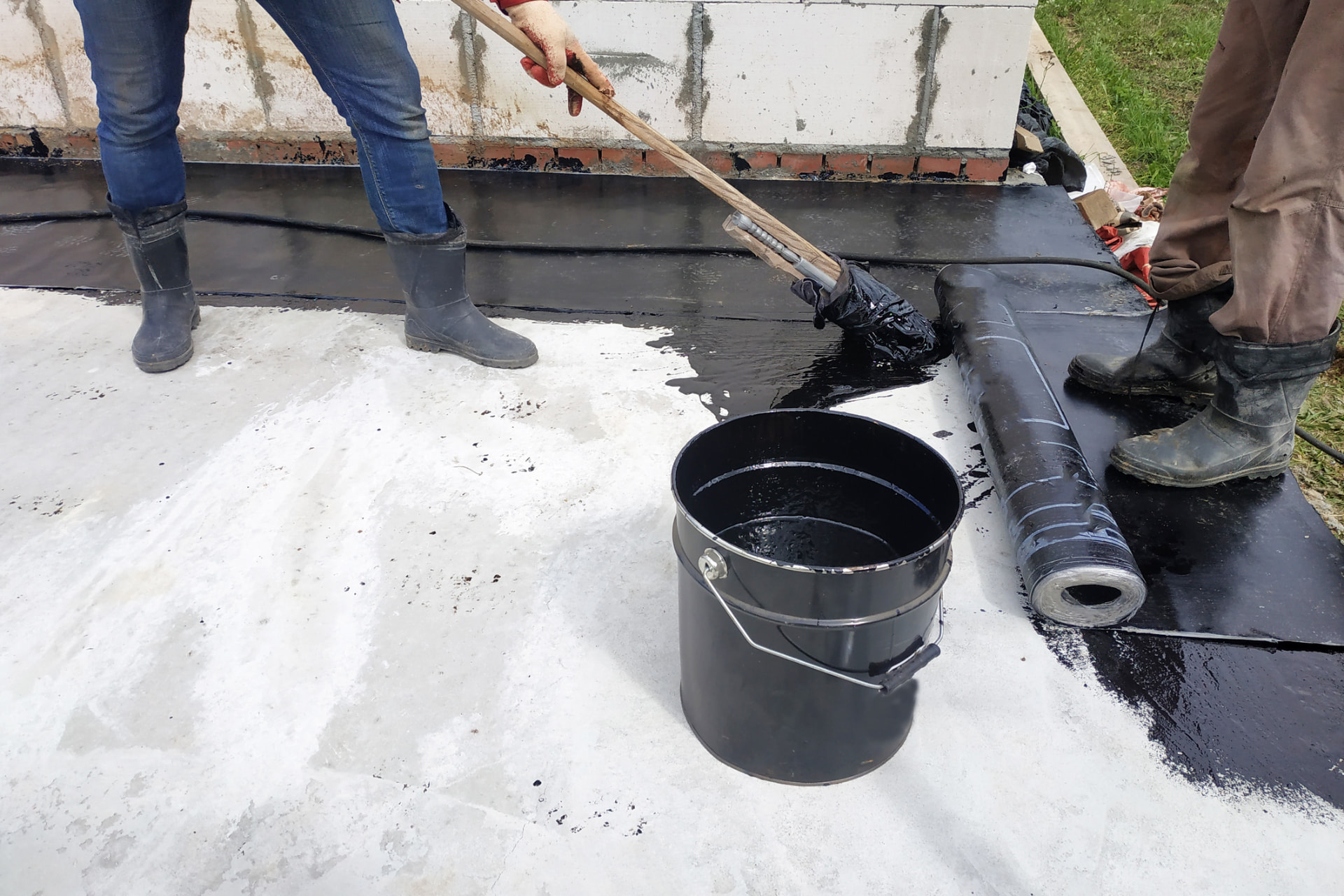 Worker brushing liquid asphalt sealer over a prepared surface in Shamong, NJ