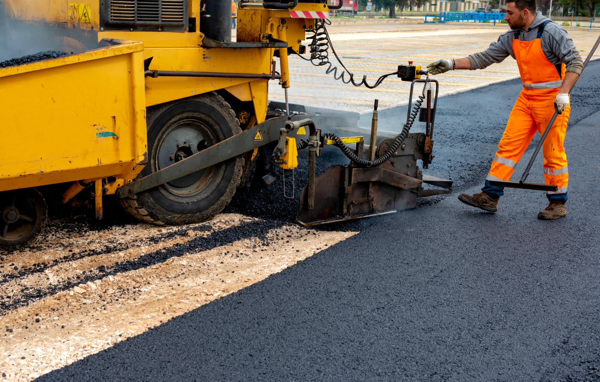 Paver laying a new asphalt surface across a commercial parking lot